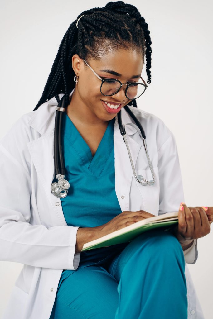 pexels photo 19131211 19131211 Smiling female doctor in scrubs with stethoscope reviewing patient notes indoors.